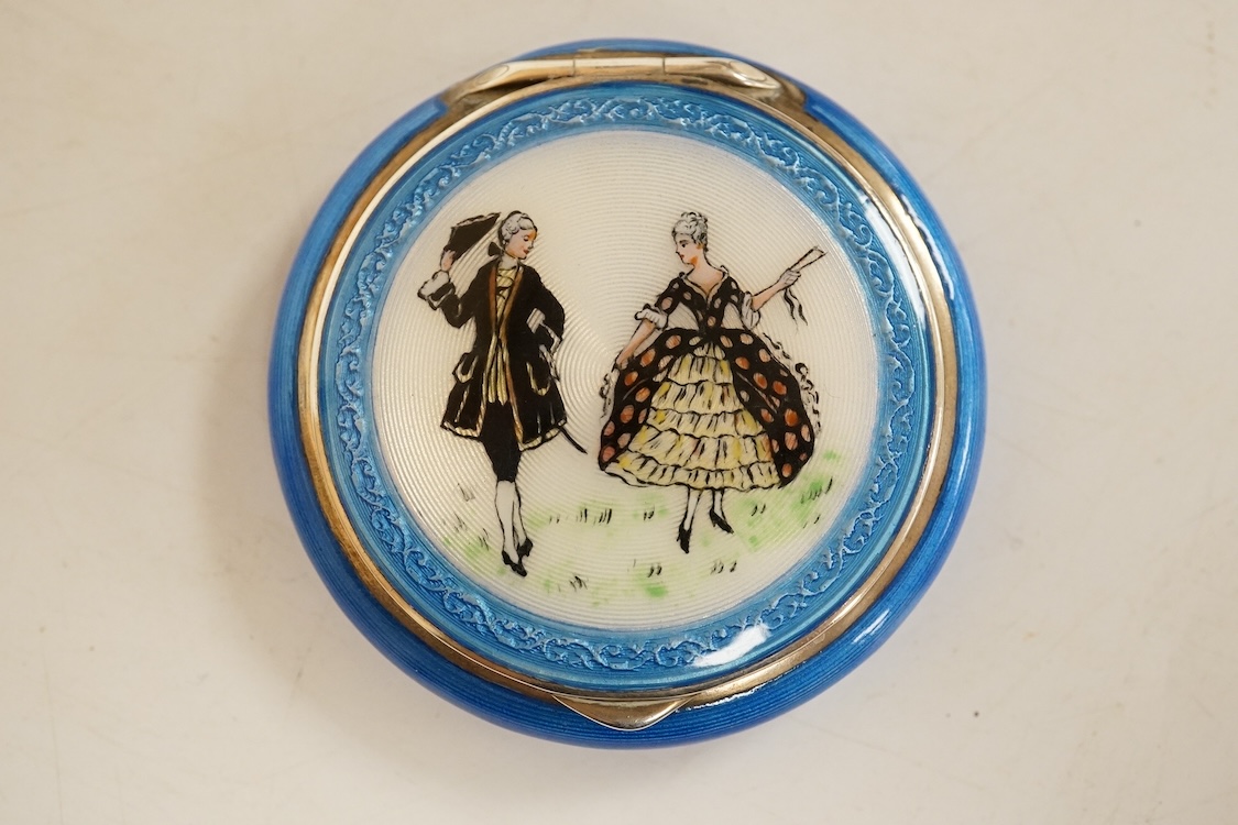 A George V silver and enamelled circular compact, the cover depicting a lady and gentleman, import marked for P.H. Vogel & Co, London, 1924, diameter 51mm.